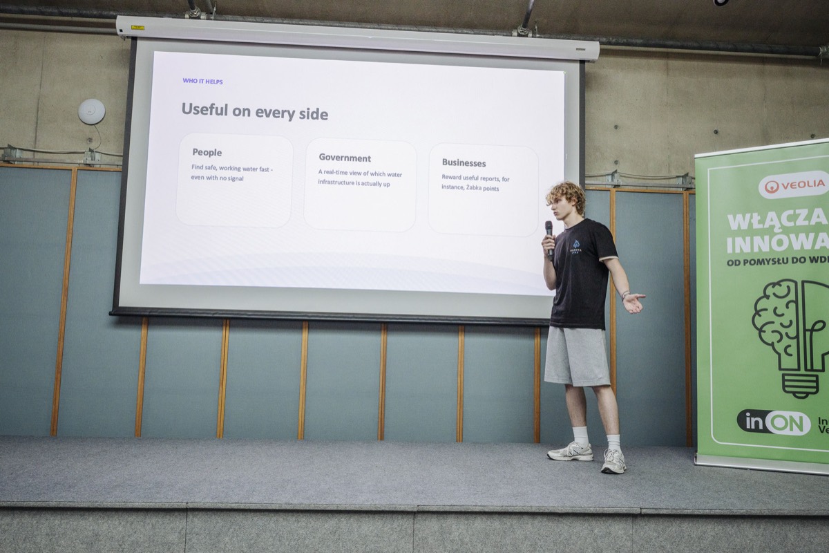 Viktor Vokh presenting the slide &ldquo;Useful on every side&rdquo; to the room, next to the Veolia innovation banner